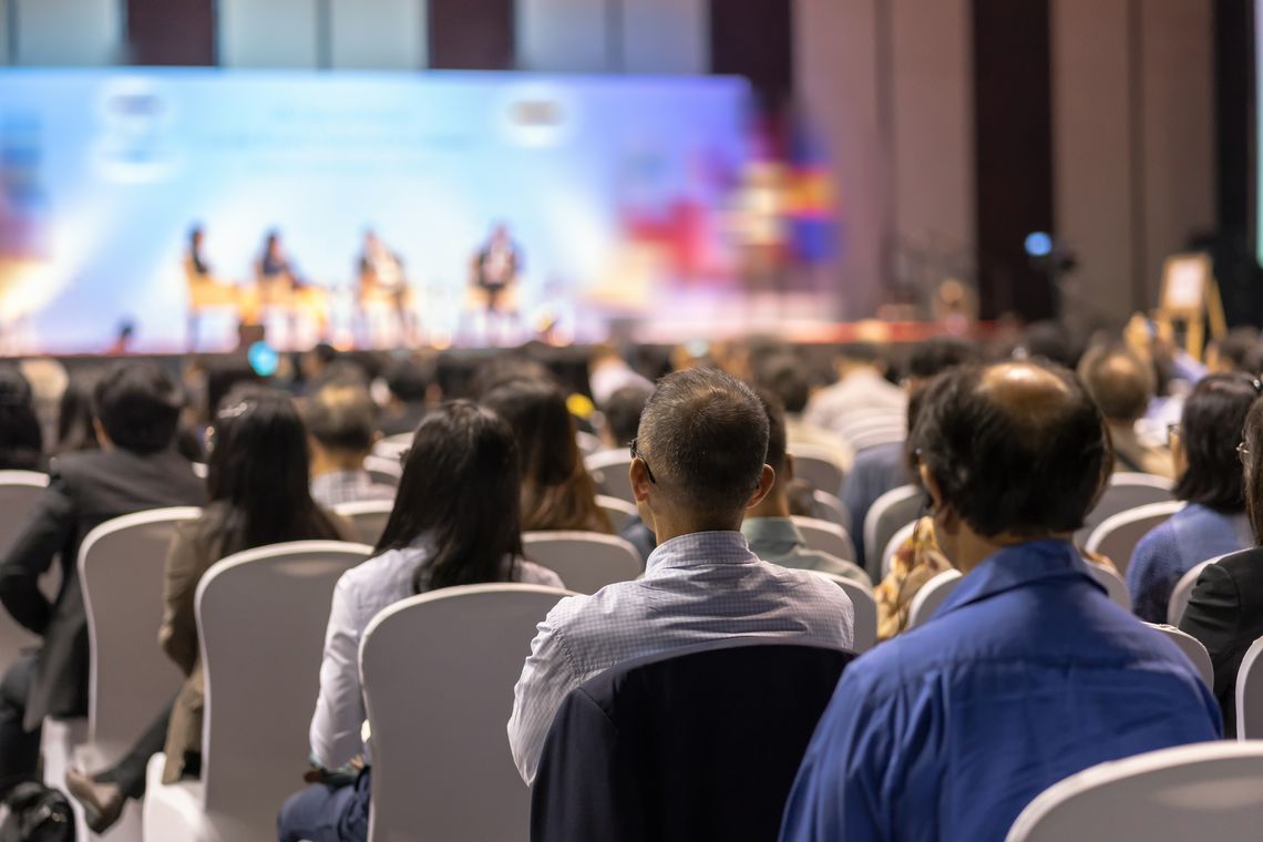 large auditorium with audience members watching a panel of speakers